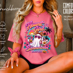 Puede incluir: Una camiseta rosa de manga corta con un gr&aacute;fico de un fantasma con gafas de sol en forma de coraz&oacute;n y un lazo de leopardo, sosteniendo una bebida y un bolso. El texto dice Haunt Girl Summerween Social Club, Comfort Colors y Crunchberry.