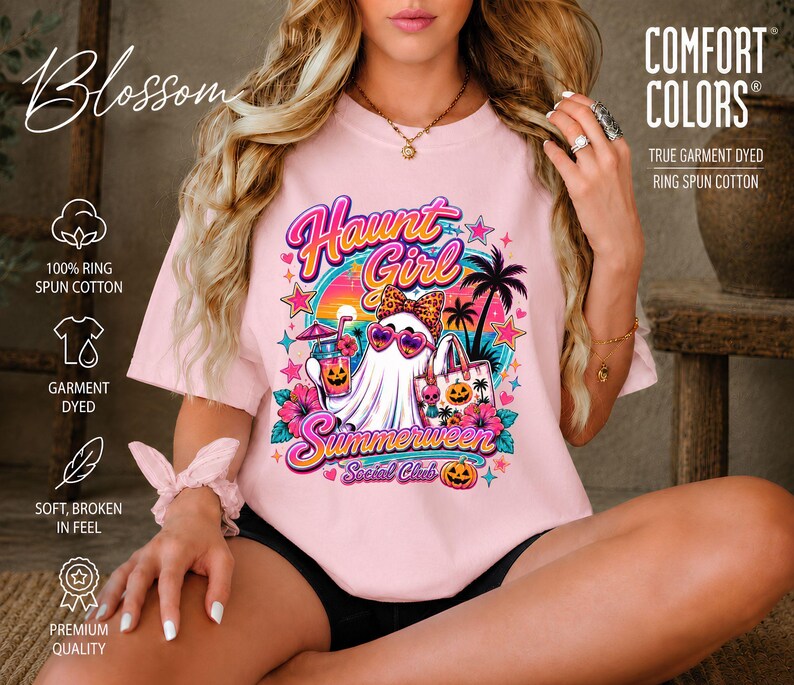 Puede incluir: Una camiseta rosa claro con un estampado gr&aacute;fico de un fantasma con gafas de sol en forma de coraz&oacute;n y un lazo de leopardo. El texto dice "Haunt Girl Summerween Social Club" en rosa y azul, con palmeras, calabazas y flores en el dise&ntilde;o.