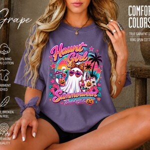 Puede incluir: Una camiseta de manga corta color uva con un estampado gr&aacute;fico de un fantasma con gafas de sol de leopardo y un lazo, sosteniendo una bebida tropical y una bolsa de tela con calabazas. El texto dice Haunt Girl Summerween Social Club.