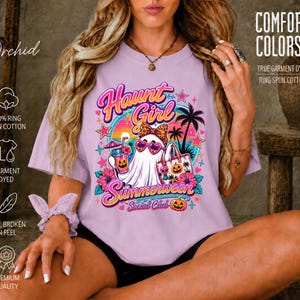 Puede incluir: Una camiseta de color morado claro con un gr&aacute;fico de un fantasma con gafas de sol en forma de coraz&oacute;n, sosteniendo una bebida y una bolsa. El texto dice Haunt Girl Summerween Social Club, con palmeras, flores y calabazas.