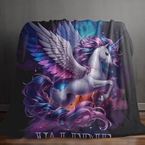 May include: A plush blanket featuring a majestic white unicorn with large, detailed wings and a flowing mane and tail in shades of purple and blue. The background is a vibrant nebula of purples, blues, and oranges, creating a fantasy theme.