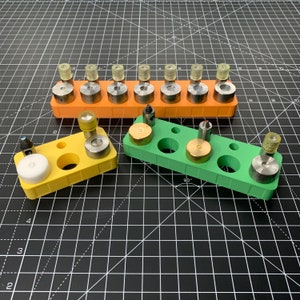 May include: Three yellow and green plastic trays with multiple small round holes. Each tray has a variety of small metal and plastic objects in the holes.