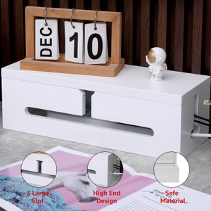 May include: A white cable management box with a wooden calendar displaying "DEC 10" and a small astronaut figurine. The box has slots for cords and the text "3 Large Slot", "High End Design", and "Safe Material".