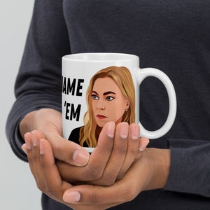 Puede incluir: Taza de cerámica blanca con una ilustración en blanco y negro de una mujer con cabello rubio. El texto "Name 'Em" está impreso en la taza.