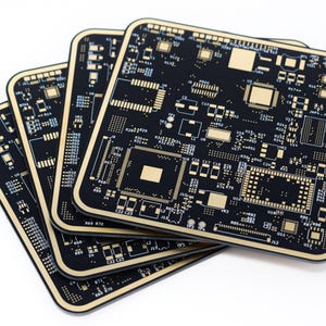 以下が含まれることがあります： 金色の回路パターンが施された、黒い正方形の回路基板が4枚重ねられています。基板は角が丸く、わずかに扇状に配置されており、電子部品の複雑なデザインが明らかになっています。