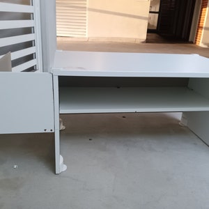 Könnte beinhalten: Ein weißer Schreibtisch mit einem Regal und einer Seitenwand. Der Schreibtisch besteht aus einem hellen Material und hat ein schlichtes, modernes Design. Der Schreibtisch ist etwa 122 cm lang und 61 cm breit.