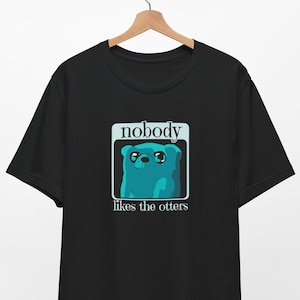 May include: Black t-shirt with a blue cartoon bear and the text "nobody likes the otters" in a white box.