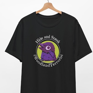 May include: Black t-shirt with a purple bird graphic and the text "Hide and Sneak #WoodlandTerrorist" in a circle.