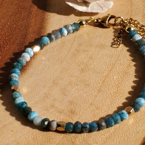 May include: A blue and green gemstone bracelet with gold accents and a gold clasp.