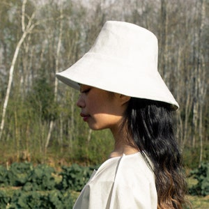 Girl wearing white Moon large brim bucket hat by Carmen Calburean.