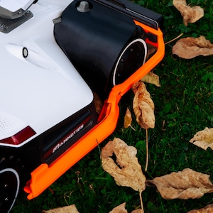 Könnte beinhalten: Eine weiße Keramiktasse mit schwarzem Henkel und dem Text "But First, Coffee" in fetter, schwarzer Schrift. Die Tasse steht vor einem verschwommenen Hintergrund, der eine gemütliche Umgebung suggeriert.
