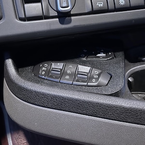 May include: A black plastic panel with a series of buttons for controlling the seat. The buttons are labelled with symbols for up, down, forward, back, and lumbar support.