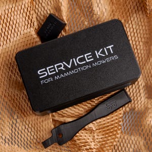 May include: A black service kit for lawn mowers, with the text "SERVICE KIT FOR MAMMOTION MOWERS" in white. The kit includes a blade and other parts, all on a brown paper background.