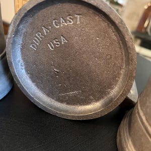 May include: Close-up of the bottom of a metal pitcher with the words "Dura-Cast USA" stamped on the bottom.