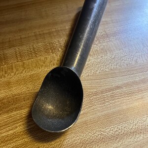 May include: A silver metal ice cream scoop with a long handle.