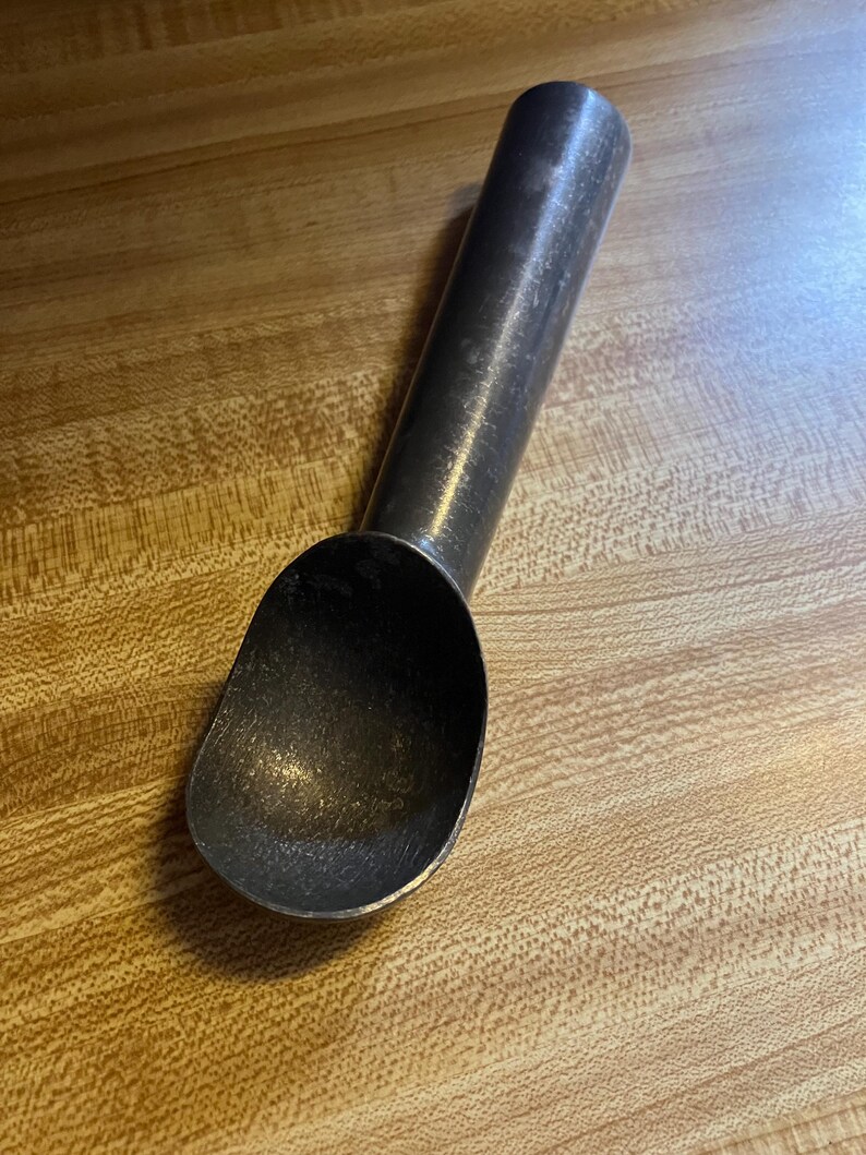 May include: A silver metal ice cream scoop with a long handle.