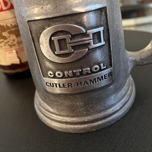 May include: A silver metal stein with a raised logo of "CH" and the text "Control Cutler-Hammer".