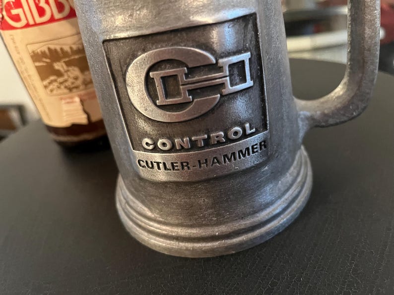 May include: A silver metal stein with a raised logo of "CH" and the text "Control Cutler-Hammer".