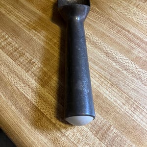 May include: A vintage metal ice cream scoop with a white plastic handle. The scoop has a worn, aged look and is perfect for serving ice cream or frozen desserts.