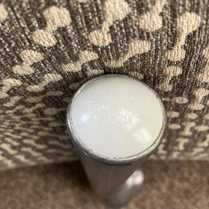 May include: A close-up of a silver metal furniture leg with a white plastic cap. The cap has the text "Made in China" printed on it.
