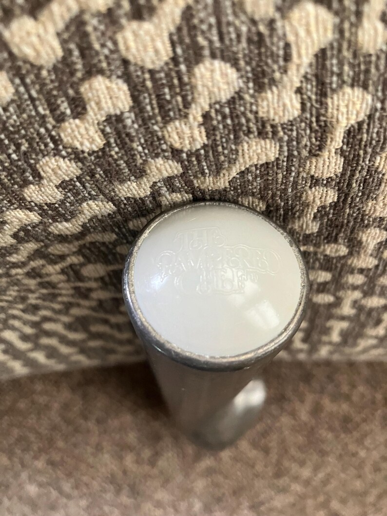 May include: A close-up of a silver metal furniture leg with a white plastic cap. The cap has the text "Made in China" printed on it.