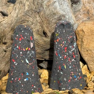 May include: Two black ceramic ghost-shaped ornaments with a speckled texture. The ornaments are decorated with colourful flecks of red, blue, green, and yellow.