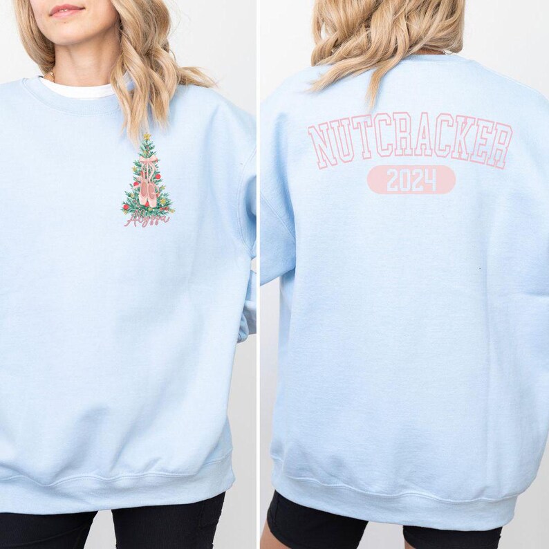 May include: Light blue sweatshirt with a Christmas tree design featuring pink ballet shoes on the front and the text "NUTCRACKER 2024" on the back.