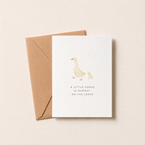 Baby Shower Card | Little Goose Illustration | Hammered Card | baby girl card | baby boy card - May include: A white greeting card featuring a watercolour illustration of an adult goose and a gosling. The text reads A LITTLE GOOSE IS ALMOST ON THE LOOSE. The card is accompanied by a brown kraft paper envelope, with a textured paper finish.