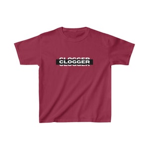 May include: A maroon t-shirt featuring the word "CLOGGER" in a white, black, and white stacked design. The shirt has a crew neck and short sleeves.