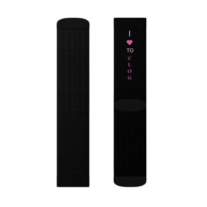 May include: Black socks with the text "I ♥ TO CLOG" in pink. The socks are made of a textured material and have a solid black colour. The text is vertically aligned on the side of the sock.