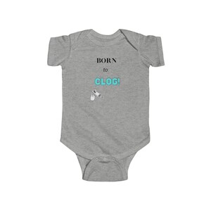 May include: A gray baby onesie with the text "BORN to CLOG!" in black and turquoise. The onesie features a small graphic of white clogs. The garment is made of soft material and has snap closures.