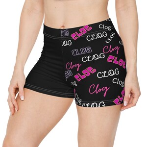 May include: Black athletic shorts featuring the word "CLOG" in white and pink lettering. The word "CLOG" is repeated in a pattern across the shorts. The shorts are form-fitting and have a high waist.