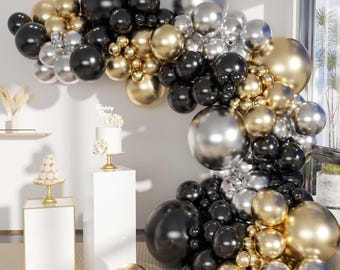 May include: A balloon arch made of black, gold, and silver balloons. The arch is decorated with a cake on a white pedestal. The balloons are arranged in a cascading pattern.