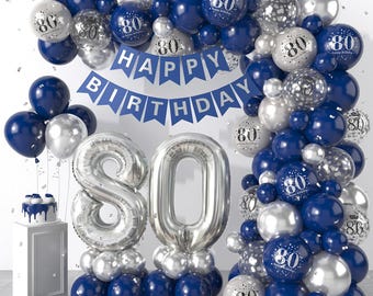 May include: A silver and blue balloon arch with a banner that reads "HAPPY BIRTHDAY". The arch is decorated with silver and blue balloons, some of which have the number "80" printed on them. There are two large silver balloons in the shape of the number "80" in the center of the image.
