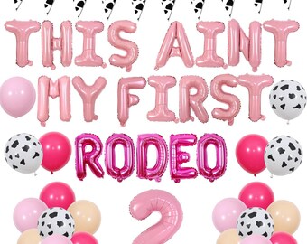 May include: Pink and white cow-print balloons, pink letter balloons spelling "This Ain't My First Rodeo", and a pink number 2 balloon.