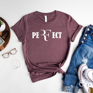May include: A maroon t-shirt with white text that reads "PERFECT" with a stylized "R" that resembles the logo of a famous tennis player.