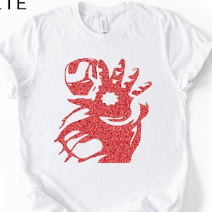 Puede incluir: Camiseta blanca con un dise&ntilde;o gr&aacute;fico rojo brillante de una mano estilizada. La palabra "WHITE" est&aacute; impresa en negro en la esquina superior izquierda. La camiseta est&aacute; hecha de un material suave.