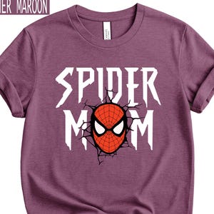 May include: Heather maroon t-shirt with rolled sleeves. The shirt features the text "SPIDER MOM" in white, with a red and black spider mask graphic in the centre. The shirt is made of a soft material.