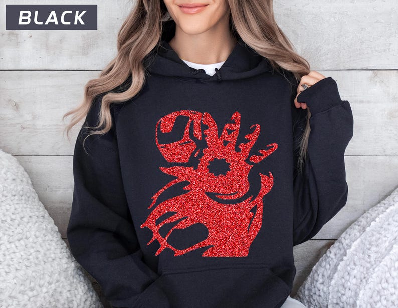 May include: Black hooded sweatshirt with a red glitter design. The design features a stylized image of a character's head and arm, with a distinctive helmet. The word 'BLACK' is displayed in a white rectangle at the top left of the image.