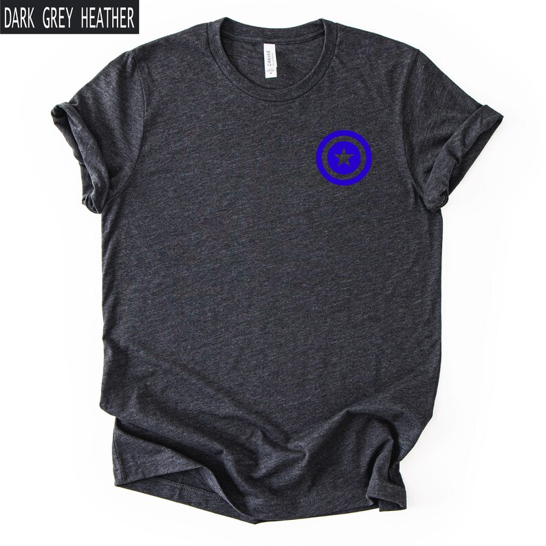 Pu&ograve; includere: T-shirt grigio scuro m&eacute;lange con grafica circolare blu sul petto. La grafica presenta una stella blu all'interno di un cerchio blu. Il testo "DARK GREY HEATHER" &egrave; in un rettangolo bianco nell'angolo in alto a sinistra.