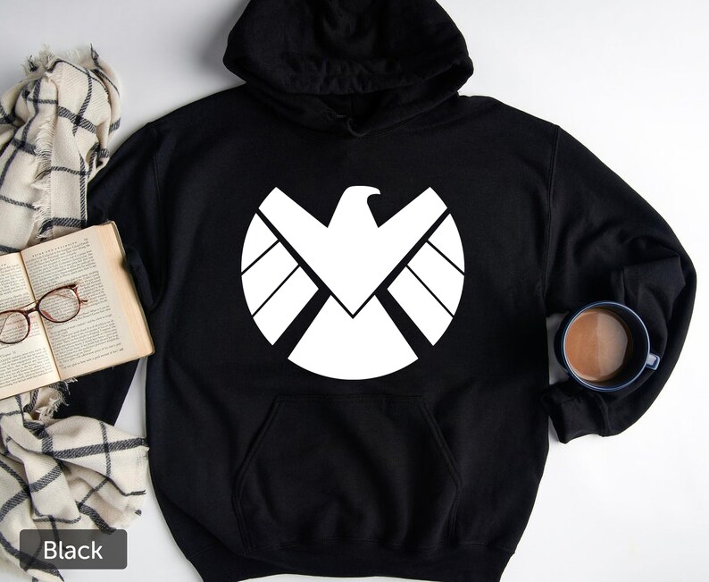 Puede incluir: Sudadera con capucha negra con un gr&aacute;fico blanco del logotipo de S.H.I.E.L.D.