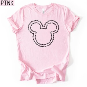 Peut inclure: Un t-shirt rose clair avec un contour noir de la t&ecirc;te de Mickey Mouse. Le contour est rempli du mot "Mickey" r&eacute;p&eacute;t&eacute;. Le mot "PINK" est dans le coin sup&eacute;rieur gauche.