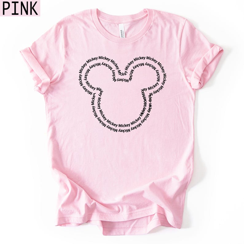 Peut inclure: Un t-shirt rose clair avec un contour noir de la t&ecirc;te de Mickey Mouse. Le contour est rempli du mot "Mickey" r&eacute;p&eacute;t&eacute;. Le mot "PINK" est dans le coin sup&eacute;rieur gauche.