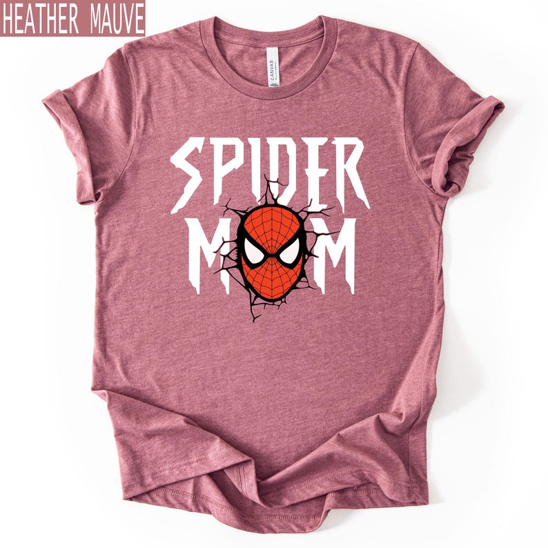 May include: Heather mauve t-shirt featuring the text "SPIDER MOM" in white, and a red and black spider mask graphic. The shirt has a crew neck and is made of a soft material. The text "HEATHER MAUVE" is in the top left corner.