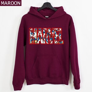 Puede incluir: Sudadera con capucha de color granate con la palabra "MARVEL" en letras con contorno rojo. Las letras est&aacute;n rellenas de im&aacute;genes de Spider-Man. La sudadera tiene un bolsillo delantero y una capucha con cord&oacute;n.
