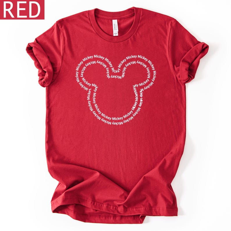 Peut inclure: Un t-shirt rouge avec un motif de t&ecirc;te de Mickey Mouse blanc. Le motif est compos&eacute; du mot "Mickey" r&eacute;p&eacute;t&eacute; en cercle. Le mot "RED" est dans le coin sup&eacute;rieur gauche.