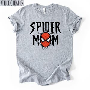 May include: Grey t-shirt with the text "SPIDER MOM" in black, featuring a red and white Spider-Man mask graphic. The shirt is made of a soft material and has a crew neck.