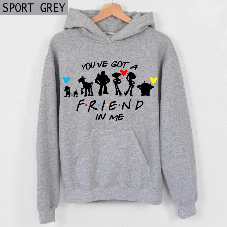 Puede incluir: Sudadera con capucha gris deportivo con un gr&aacute;fico frontal que presenta siluetas de personajes y el texto "YOU'VE GOT A FRIEND IN ME". El dise&ntilde;o incluye corazones coloridos y detalles de personajes. La sudadera tiene capucha y bolsillo delantero.