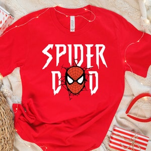 K&ouml;nnte beinhalten: Rotes T-Shirt mit einer wei&szlig;en Grafik, auf der "Spider Dad" steht, mit einem Cartoon-Bild von Spider-Mans Gesicht.