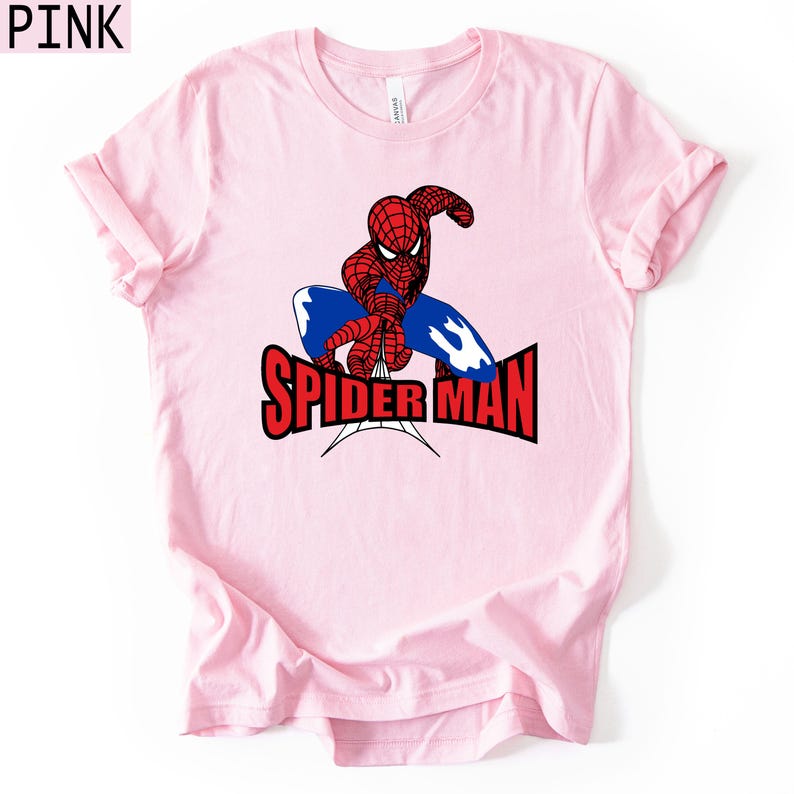 Op de afbeelding: Lichtroze t-shirt met een afbeelding van Spider-Man in rood en blauw, en de woorden "SPIDER-MAN" in rood en zwart. Het shirt heeft korte mouwen en een ronde hals.